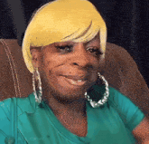 a woman wearing hoop earrings and a yellow wig smiles