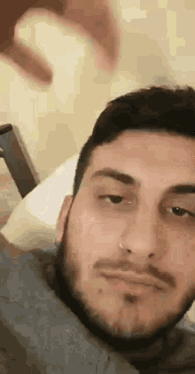 a man with a beard is laying on a bed and making a funny face .