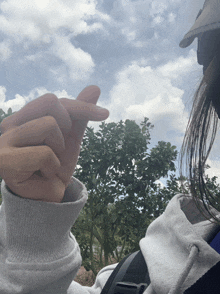 a person wearing a white sweatshirt is making a heart shape with their hand