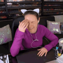 a woman wearing a cat ear headband is covering her eyes with her hand