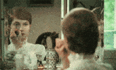 a woman applies makeup in front of a mirror