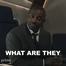a man in a suit and tie is holding a glass of water and says " what are they "