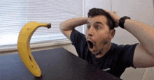 a man is sitting at a table with his mouth open and a banana on it