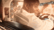 a man in a white shirt is driving a car with a fire coming out of the window