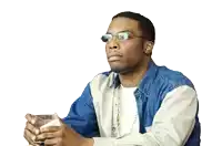 a man wearing glasses and a denim shirt is holding a glass of water