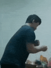 a man in a black shirt is standing in a room with his hands in the air .