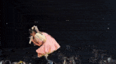 a woman in a pink dress is singing into a microphone on a stage in front of a crowd .