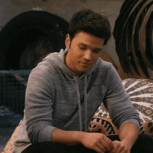 a man in a grey sweater is sitting on a couch