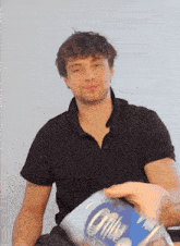 a man in a black shirt is holding a can of coffee in his hand .