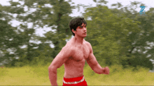 a man without a shirt is running in a field with the letter z behind him
