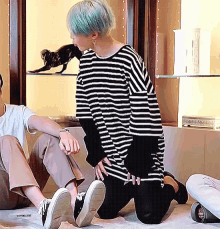 a person wearing a black and white striped shirt is kneeling on the floor