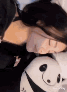 a woman is sleeping on a bed next to a panda stuffed animal .