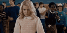 a girl with blonde hair is standing in a crowd of people .