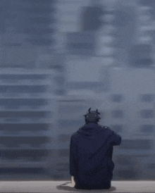 a man in a long black coat is standing in front of a blue wall