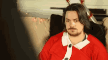 a man with long hair and a beard is wearing a santa outfit