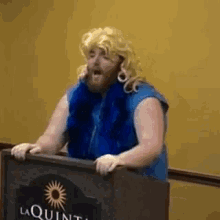 a man is standing at a podium in front of a sign that says laquinta .