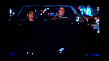 two men are sitting in a car with the word exit on the back window