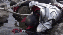 a person in armor is laying on the ground in a puddle of water