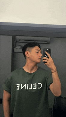 a man taking a picture of himself in the mirror wearing a green celine shirt
