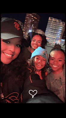 a woman wearing a san francisco giants hat poses for a picture with two other girls