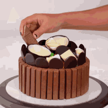a person is putting a kitkat bar on top of a chocolate cake
