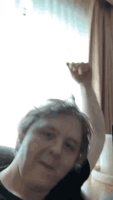 a man is sitting in front of a window with his arm up in the air .