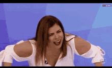 a woman is making a funny face while sitting on a blue background .