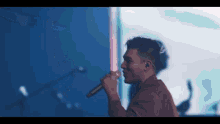 a man is singing into a microphone in front of a blue background