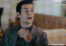 a man in a suit has his hands folded in front of his face