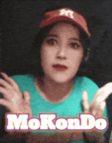 a woman wearing a red hat and a blue shirt with the words mokondo on the bottom
