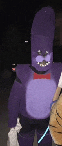 a person in a purple bonnie costume is standing next to another person .