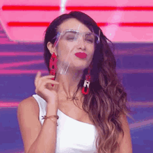 the woman is wearing a face shield and red earrings .