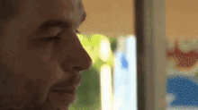 a close up of a man 's face looking out a window