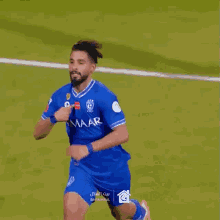 a soccer player wearing a blue shirt and shorts is running on the field .