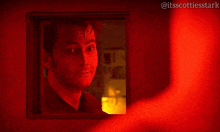 a man is looking out of a window with a red light behind him and the hashtag @itsscottiesstark