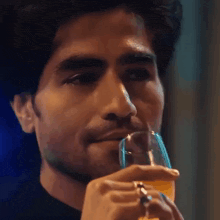 a close up of a man drinking a glass of beer .