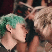 a man with green hair and a woman with blonde hair are looking at each other .