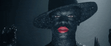 a man with a hat and red lips is covered in black glitter