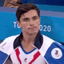 a man in a blue and white jacket is looking at the camera .