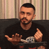 a man with a beard is sitting on a couch with his hands out
