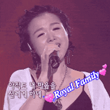 a woman singing into a microphone with royal family written on the bottom right