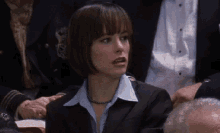 a woman in a suit and blue shirt is sitting in a crowd