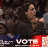 a woman stands in front of an advertisement for the nba all star voting