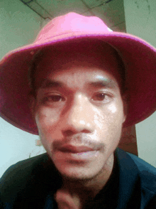 a man wearing a pink hat looks at the camera with a serious look on his face