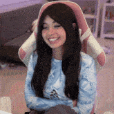 a woman in a blue shirt is sitting in a pink chair with her arms crossed