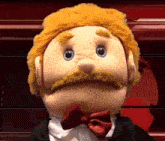 a puppet with a mustache and a bow tie is wearing a tuxedo