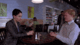 a man and a woman sit at a table with salt and pepper shakers on the table