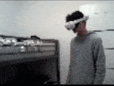 a man wearing a virtual reality headset is standing in a room with bunk beds .