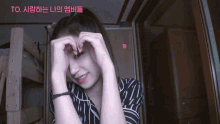 a woman making a heart shape with her hands with a heart sticker on her forehead that says to