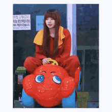 a girl in a red outfit is sitting on a toy car .